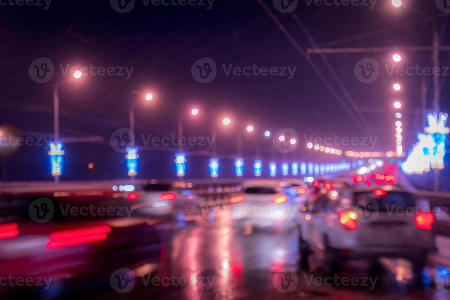 Blurry lights of moving cars and lanterns reflecting on the wet asphalt in the night city. photo