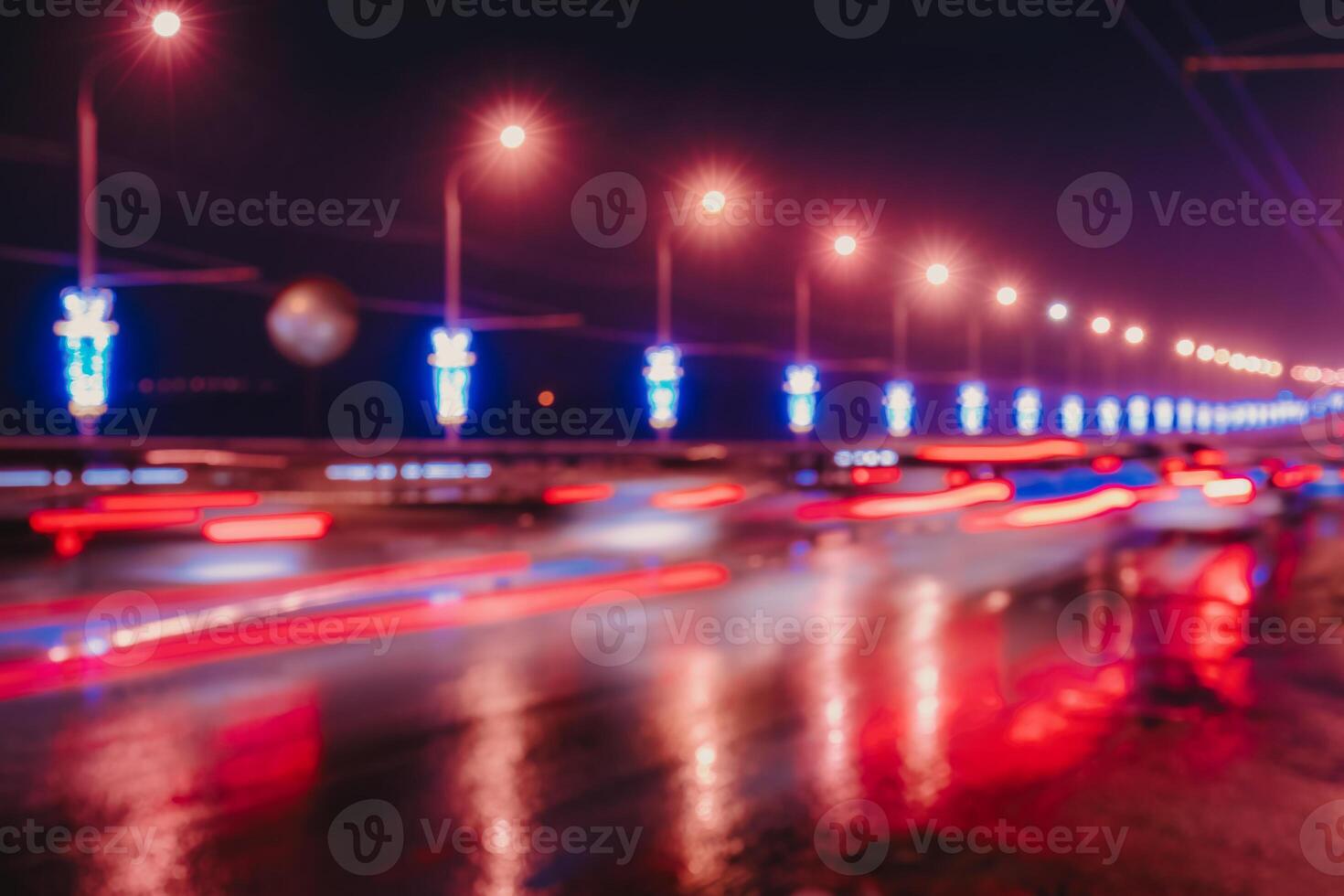 Blurry lights of moving cars and lanterns reflecting on the wet asphalt in the night city. photo
