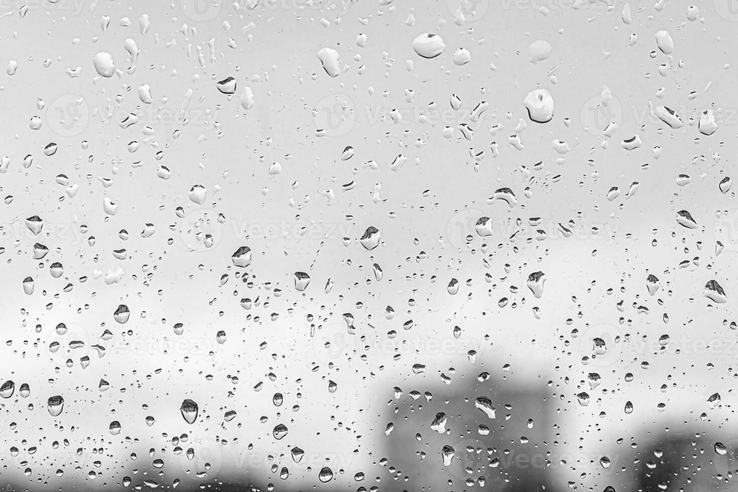 Rain drops on window glasses surface with gray sky and buildinhs background. The concept of bad rainy weather. photo