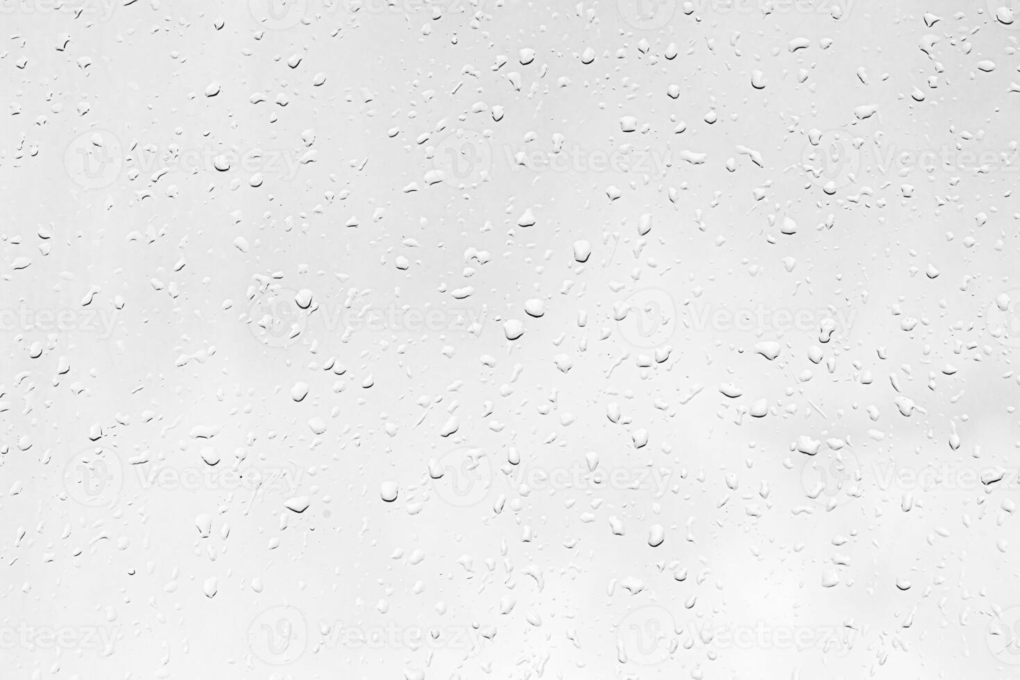 Rain drops on window glasses surface with gray sky background. Natural backdrop of raindrops. The concept of bad rainy weather. photo