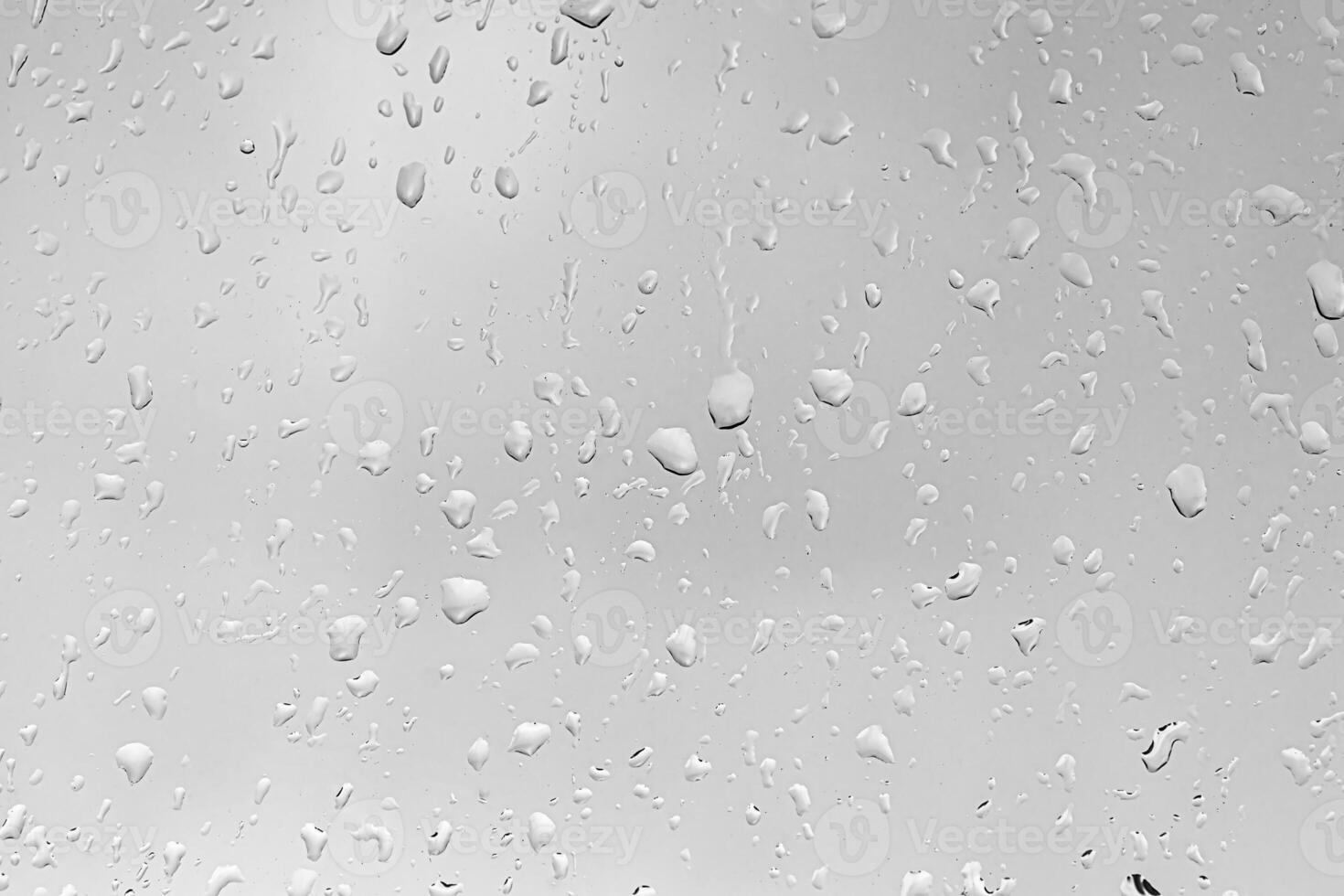 Rain drops on window glasses surface with gray sky background. Natural backdrop of raindrops. The concept of bad rainy weather. photo