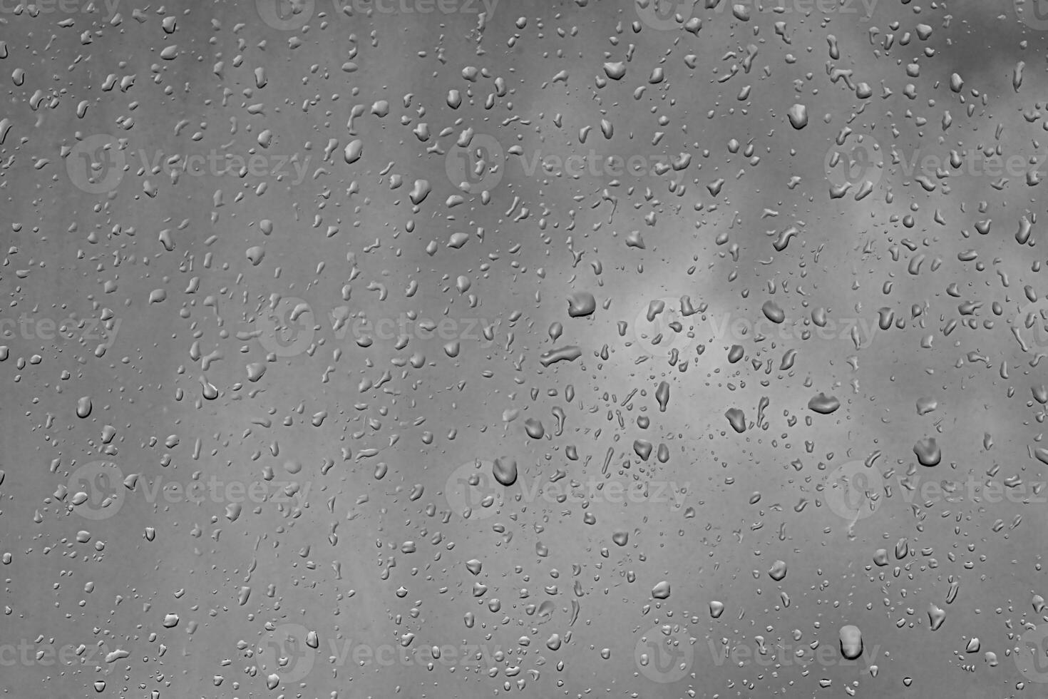 Rain drops on window glasses surface with gray sky background. Natural backdrop of raindrops. The concept of bad rainy weather. photo