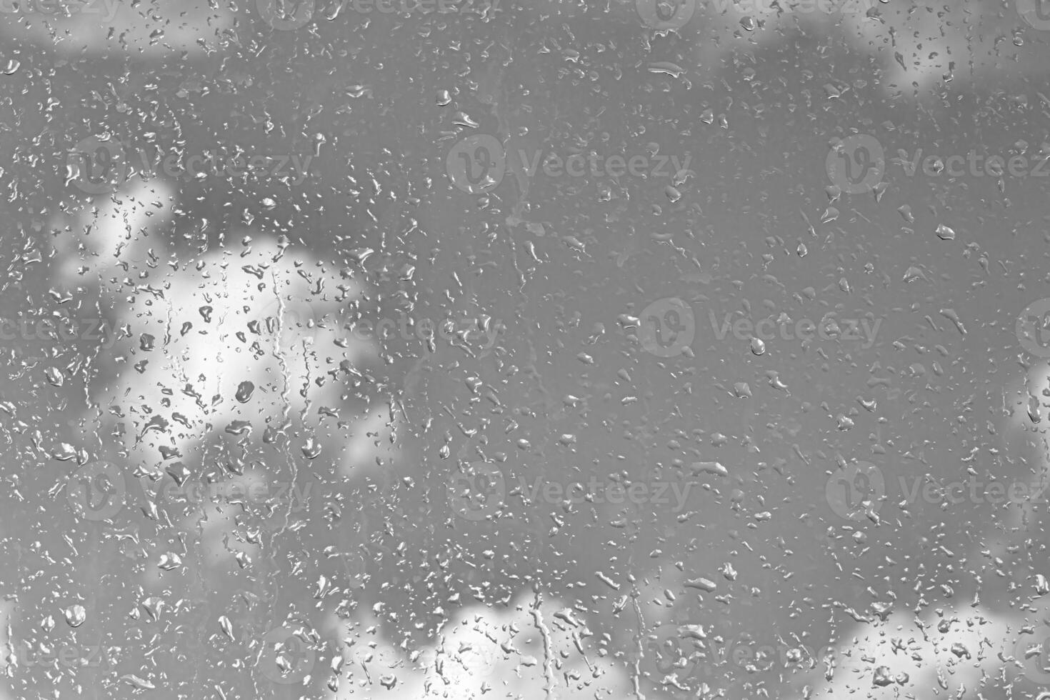 Rain drops on window glasses surface with gray sky background. Natural backdrop of raindrops. The concept of bad rainy weather. photo
