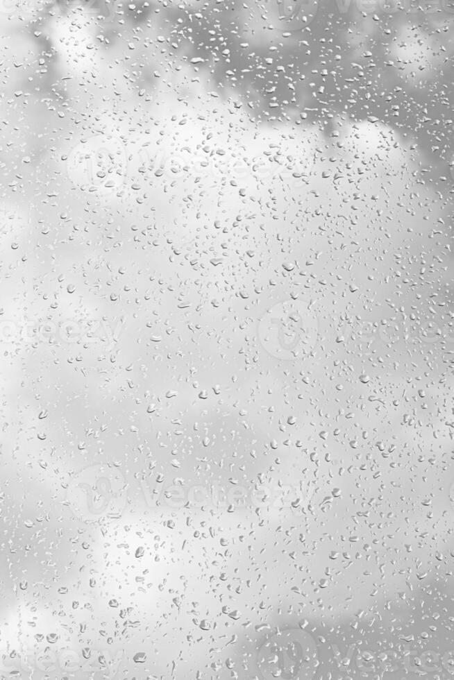 Rain drops on window glasses surface with gray sky background. Natural backdrop of raindrops. The concept of bad rainy weather. photo