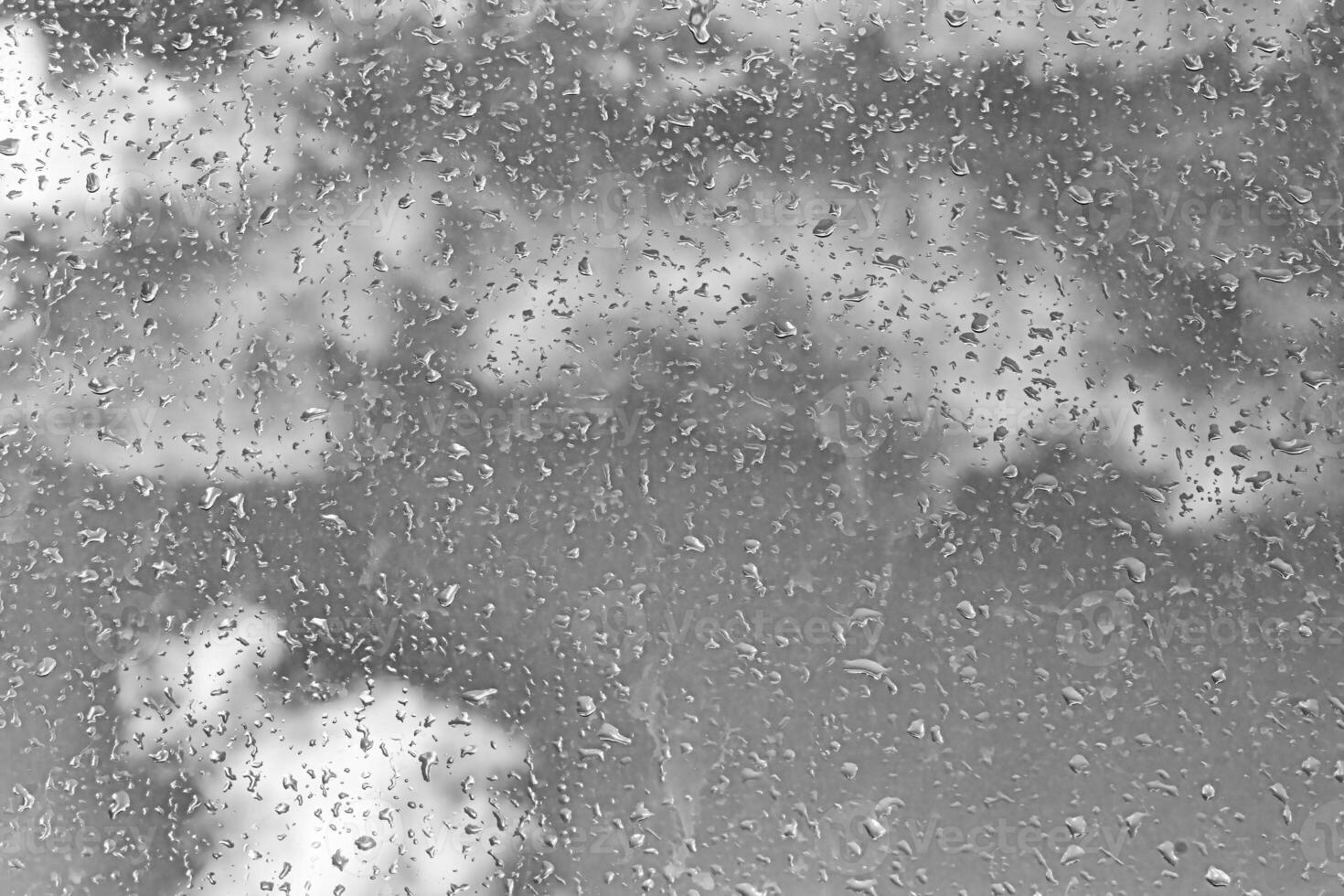 Rain drops on window glasses surface with gray sky background. Natural backdrop of raindrops. The concept of bad rainy weather. photo