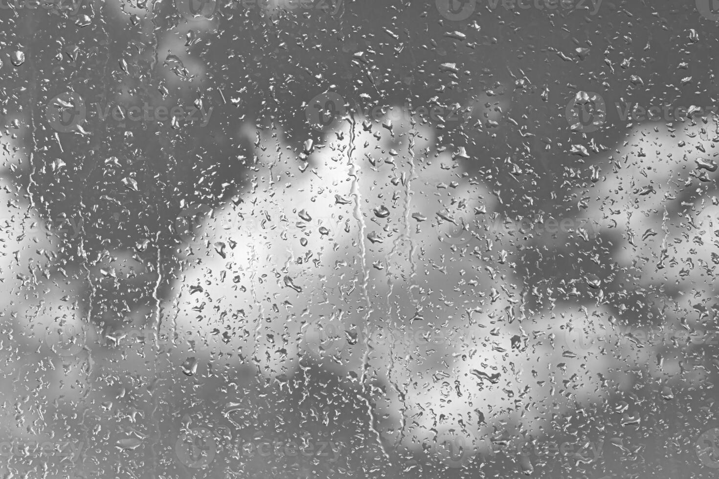 Rain drops on window glasses surface with gray sky background. Natural backdrop of raindrops. The concept of bad rainy weather. photo