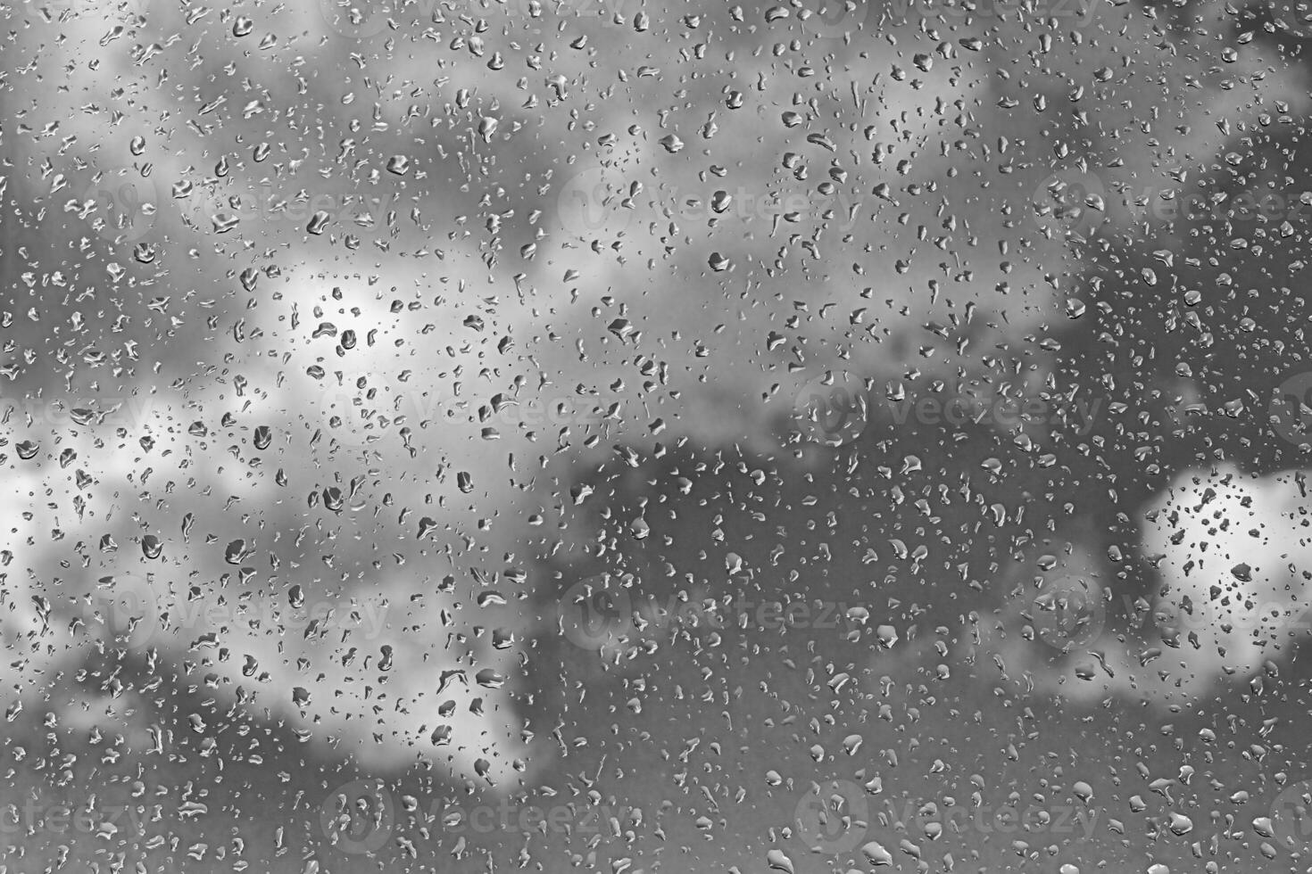Rain drops on window glasses surface with gray sky background. Natural backdrop of raindrops. The concept of bad rainy weather. photo