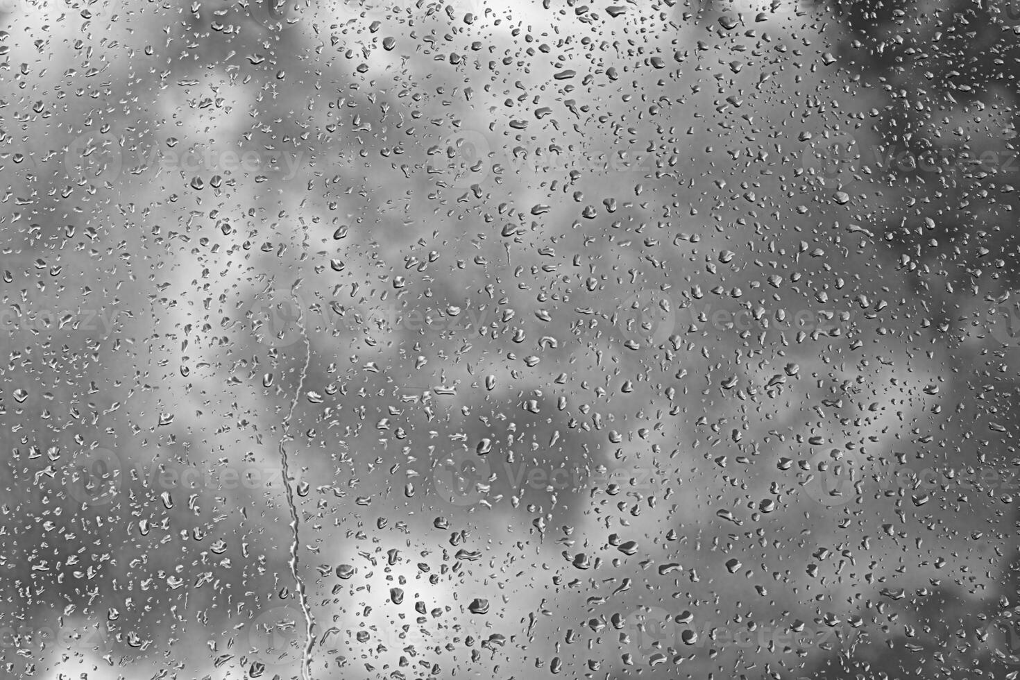 Rain drops on window glasses surface with gray sky background. Natural backdrop of raindrops. The concept of bad rainy weather. photo