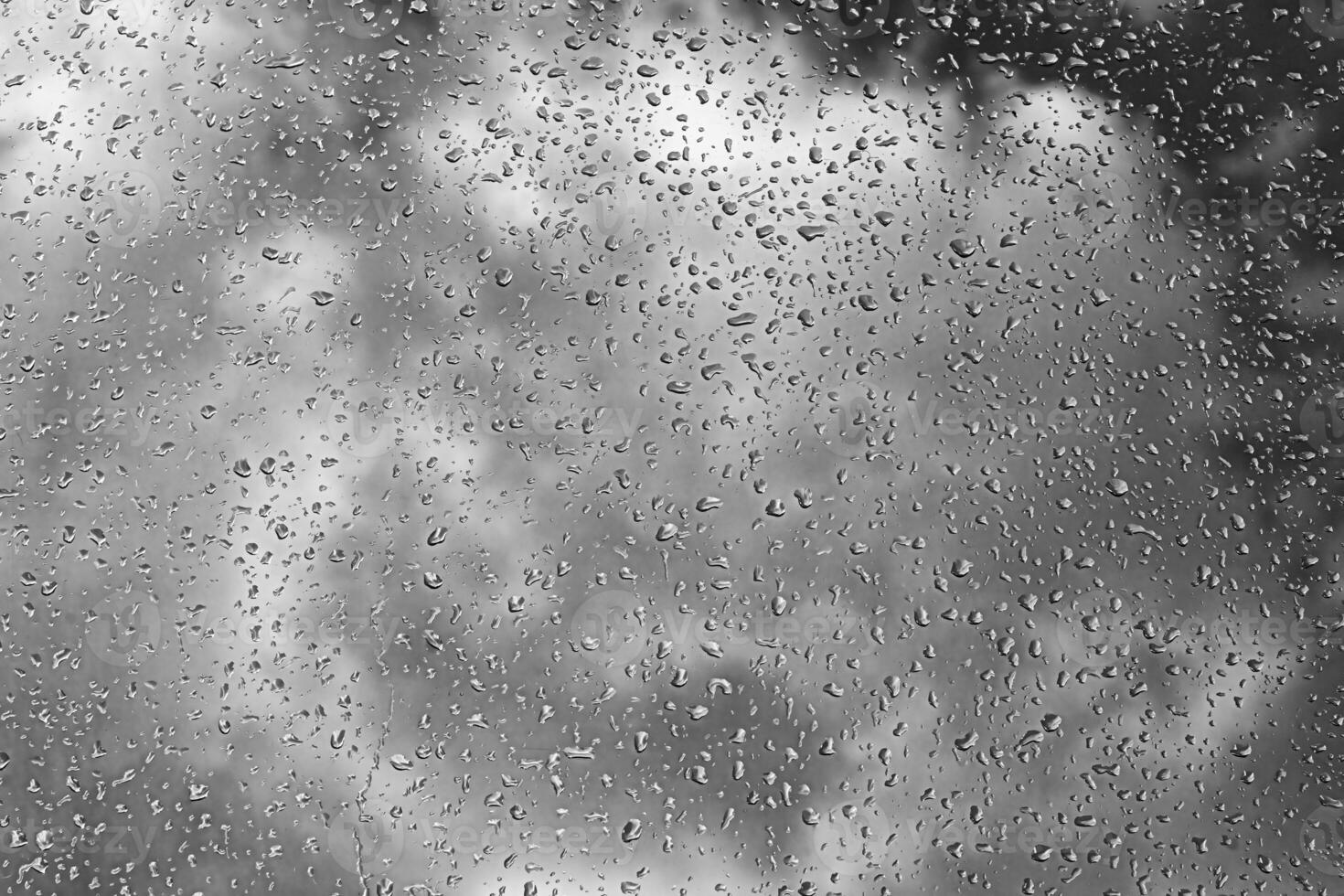 Rain drops on window glasses surface with gray sky background. Natural backdrop of raindrops. The concept of bad rainy weather. photo