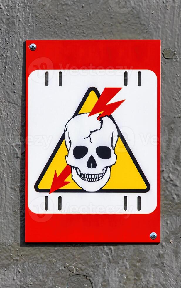 High voltage sign with lightning piercing the skull on a yellow photo