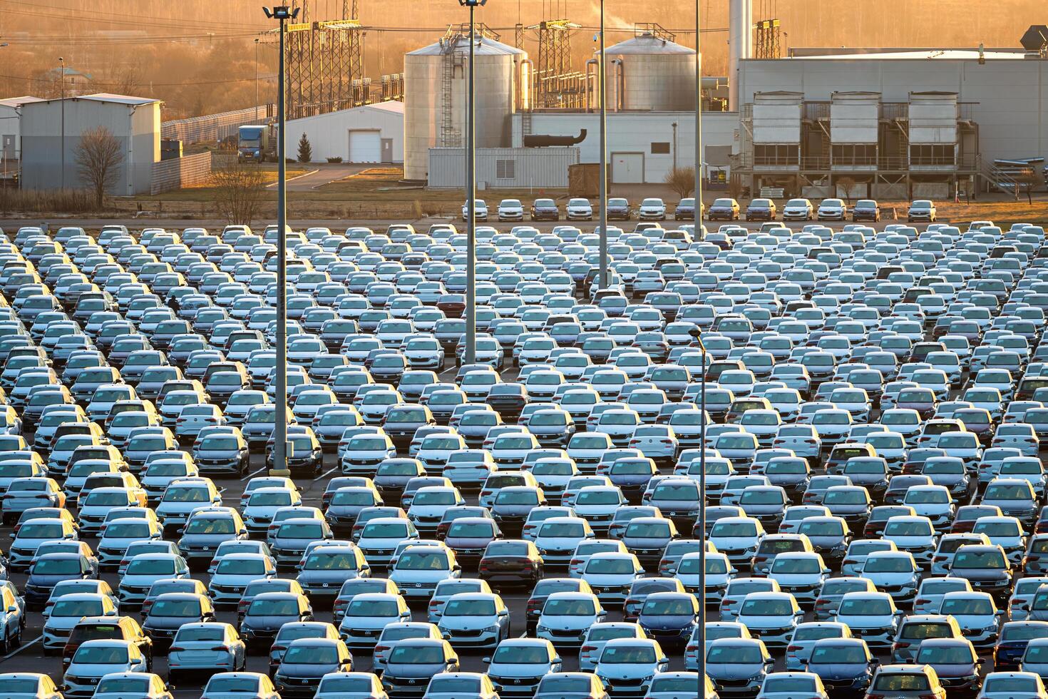 Volkswagen Group Rus, Russia, Kaluga - NOVEMBER 17, 2020 Rows of a new cars parked in a distribution center on a sunny autumn morning and a car factory buildings. photo