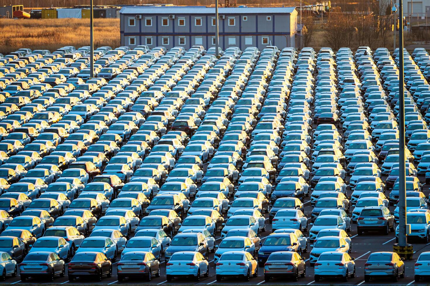 Volkswagen Group Rus, Russia, Kaluga - NOVEMBER 17, 2020 Rows of a new cars parked in a distribution center on a sunny autumn morning and a car factory buildings. photo
