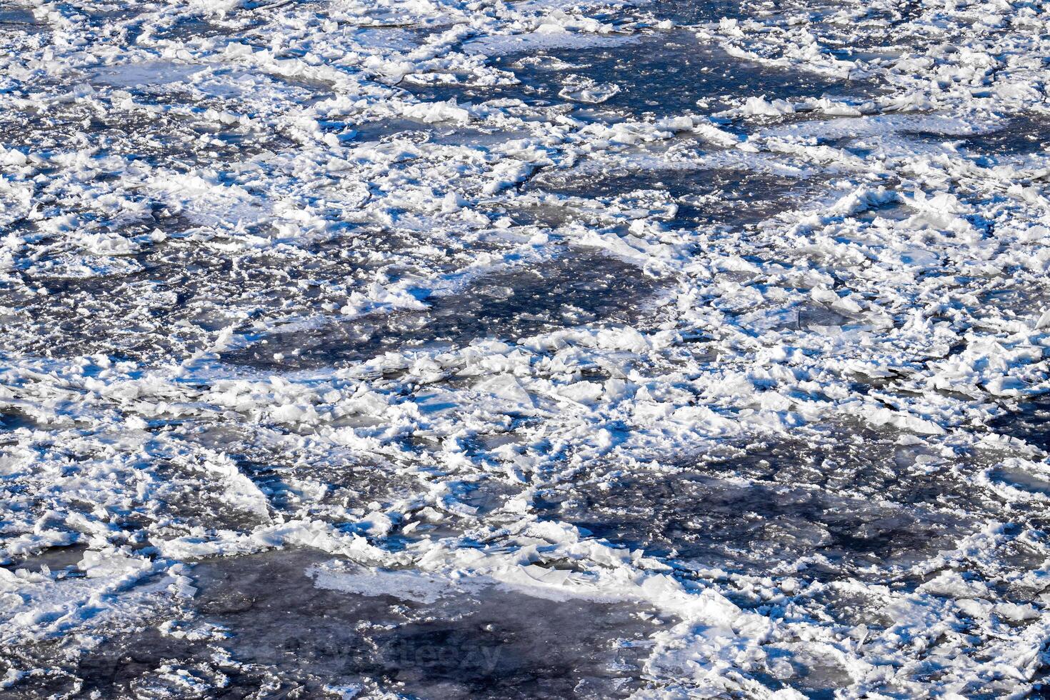 Melting ice floating on the river on a spring day. Cracked ice texture. photo