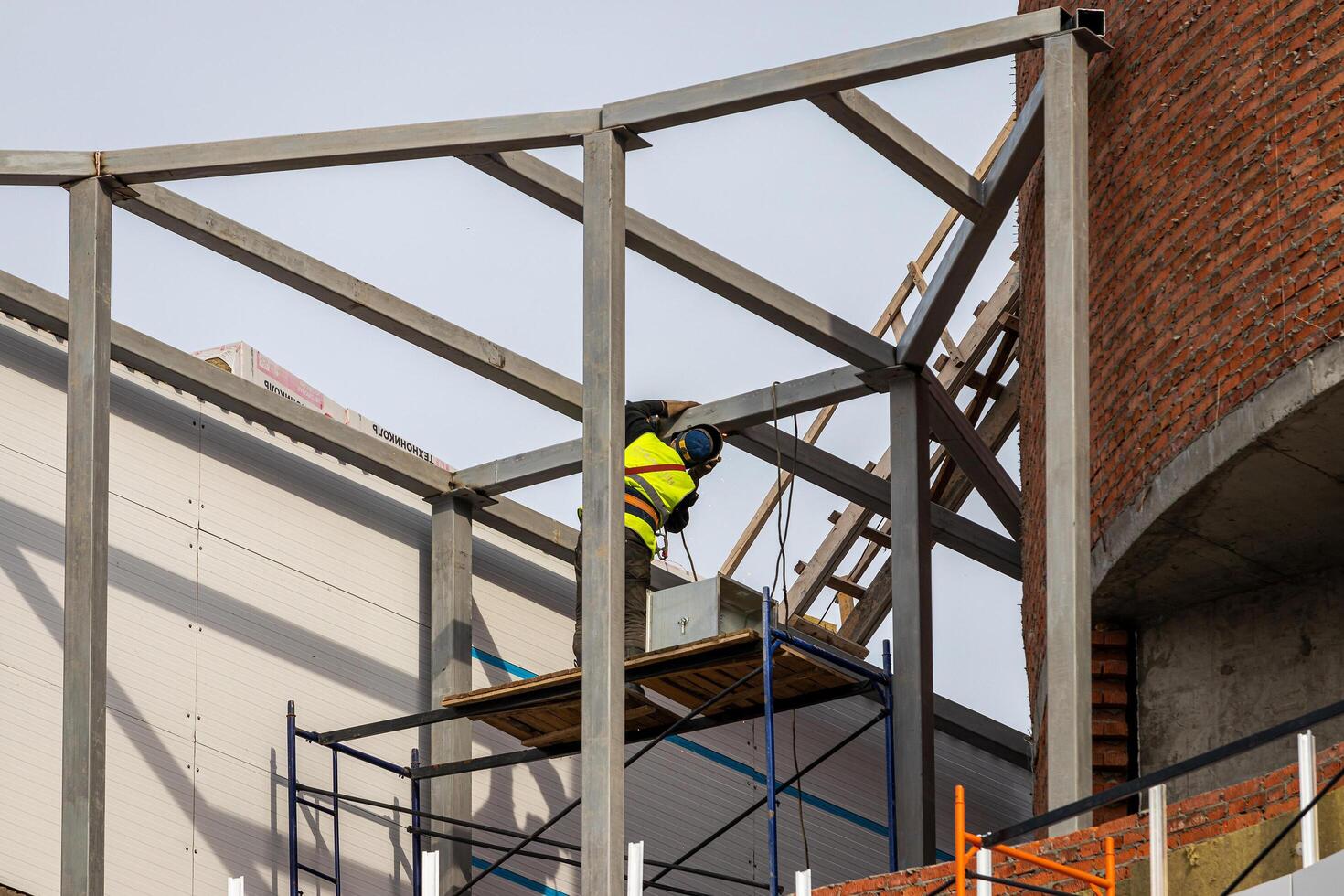 Russia, Kaluga - SEPTEMBER 16, 2020 Welder welding the metal frame of a building at a construction site on a sunny day. photo