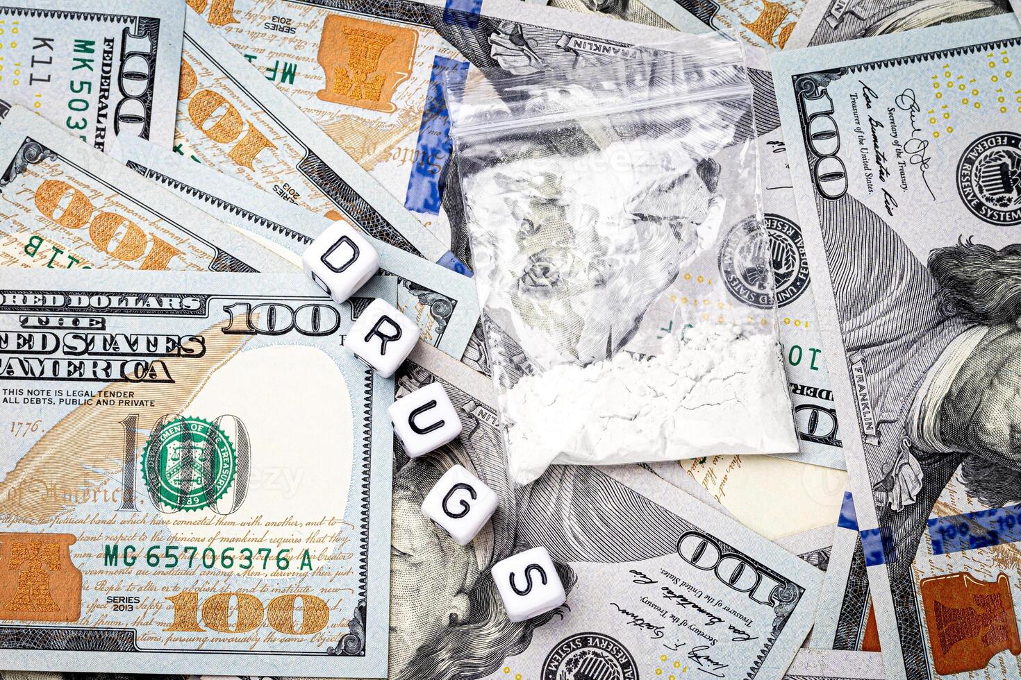 A bag with white narcotic powder like heroin or cocaine on the background of one hundred dollar bills. photo