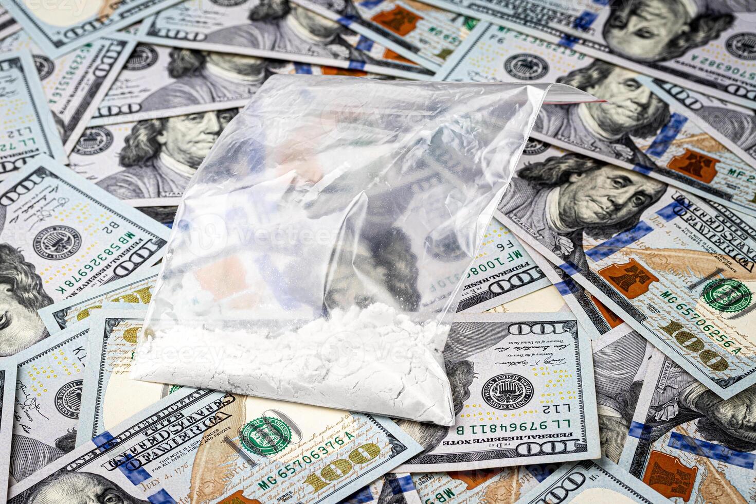 A bag with white narcotic powder like heroin or cocaine on the background of one hundred dollar bills. photo