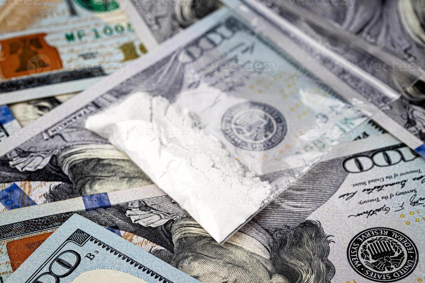 A bag with white narcotic powder like heroin or cocaine on the background of one hundred dollar bills. photo