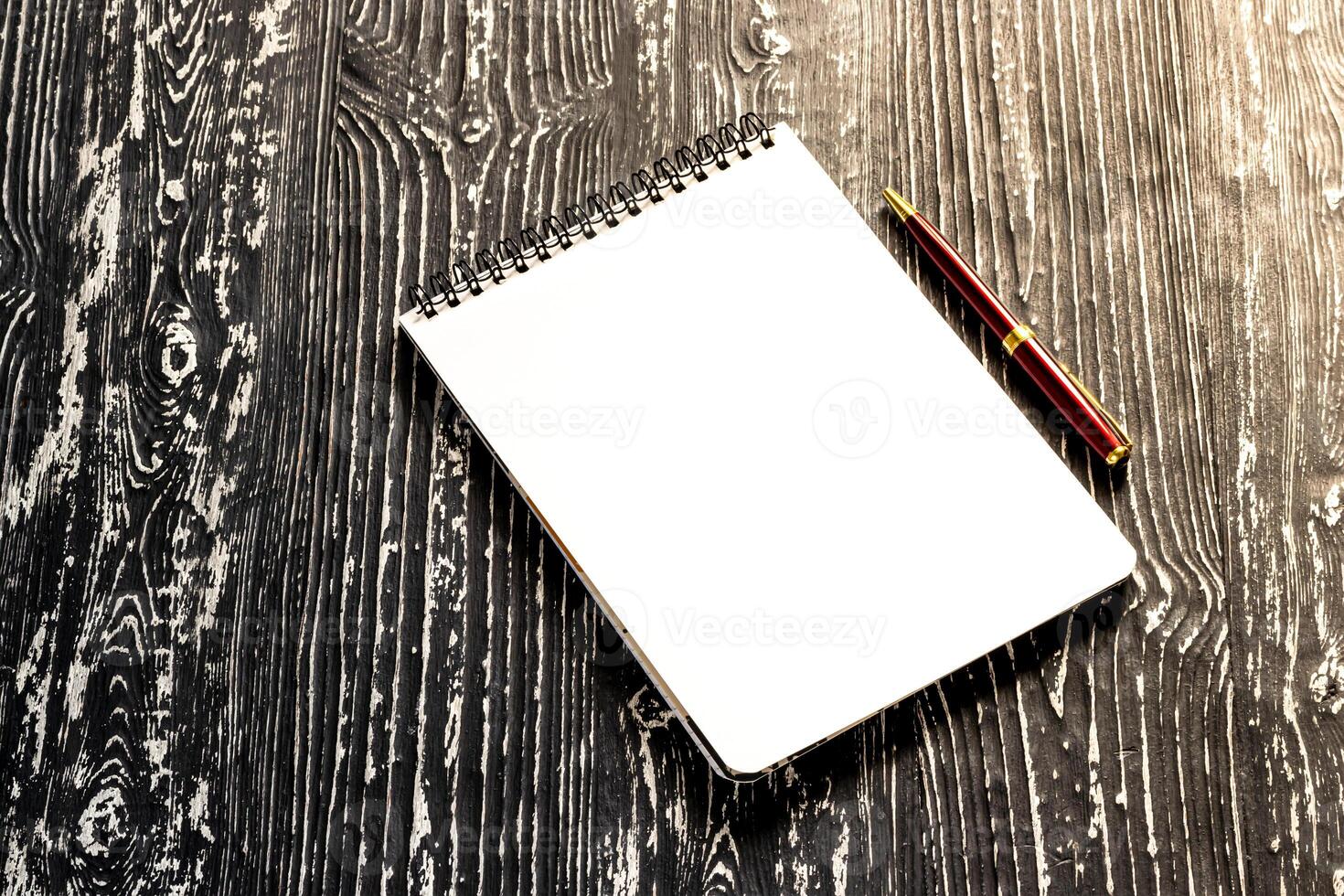 The notebook with squared pages and pen on a black table with a copy space. photo
