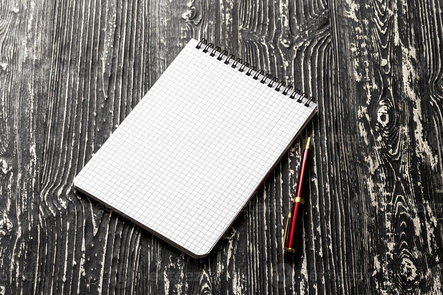 The notebook with squared pages and pen on a black table with a copy space. photo