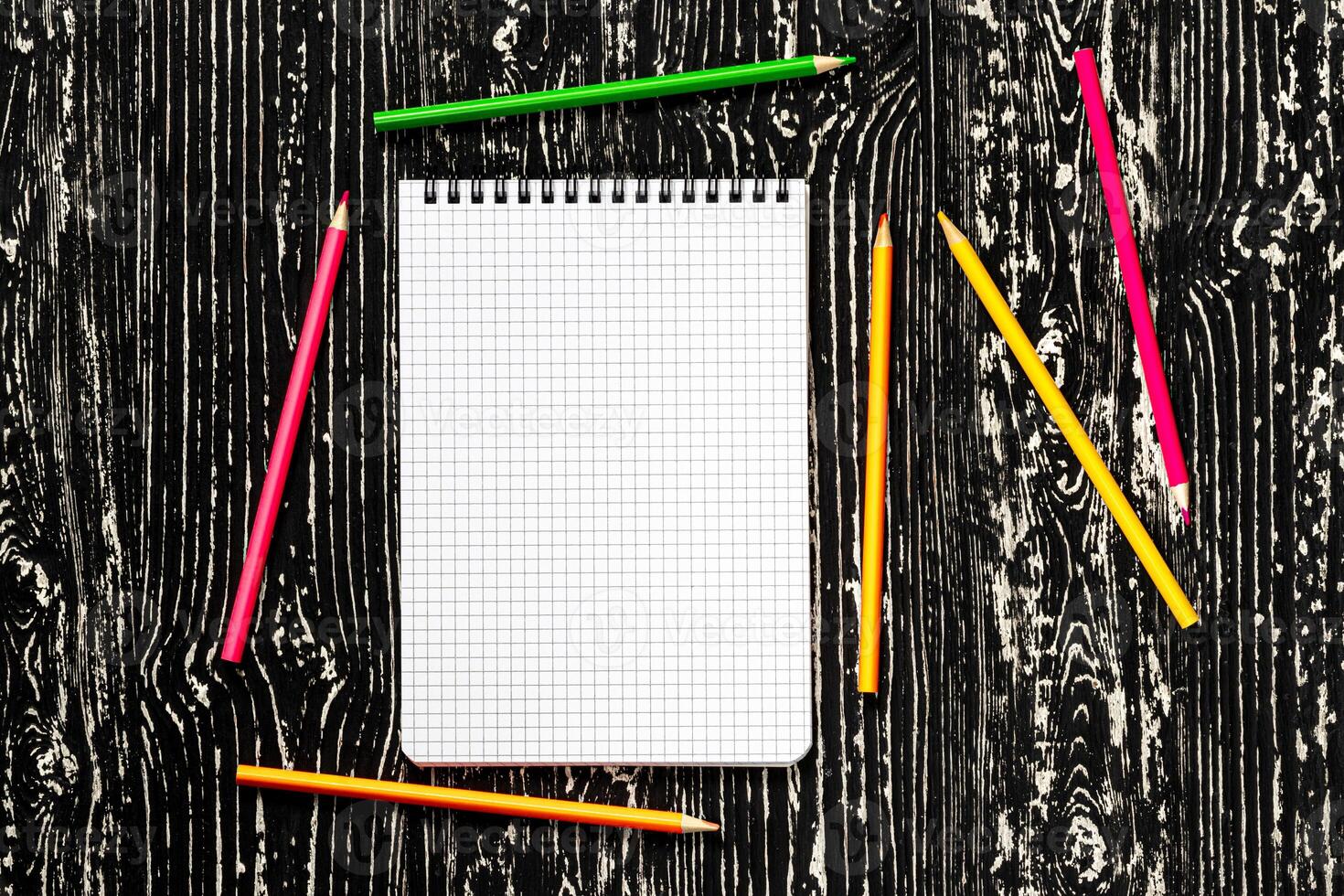 The notebook with squared pages and colorful pencils on a black table with a copy space. photo