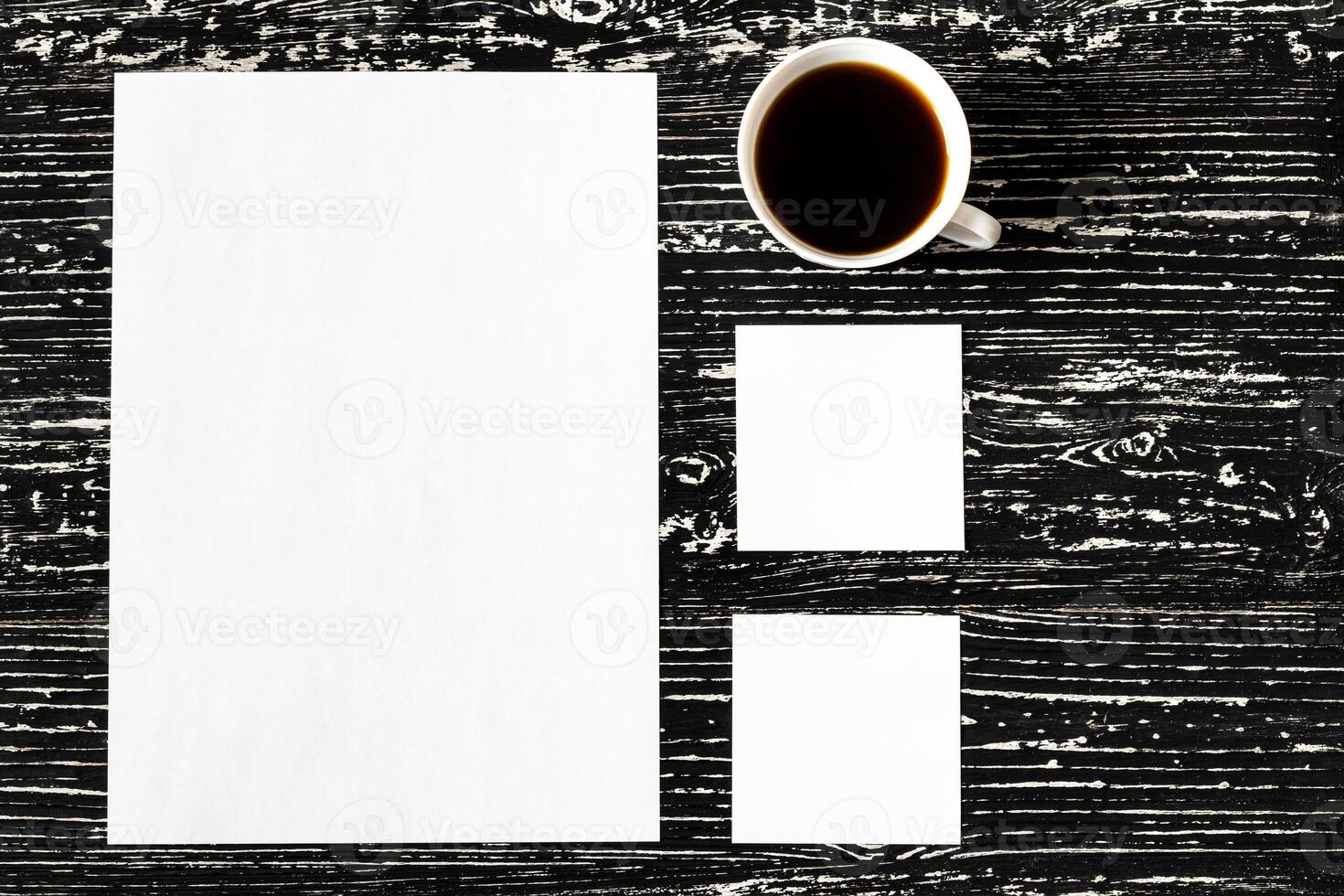 White paper sheets and cup of coffee on a black wooden table. photo