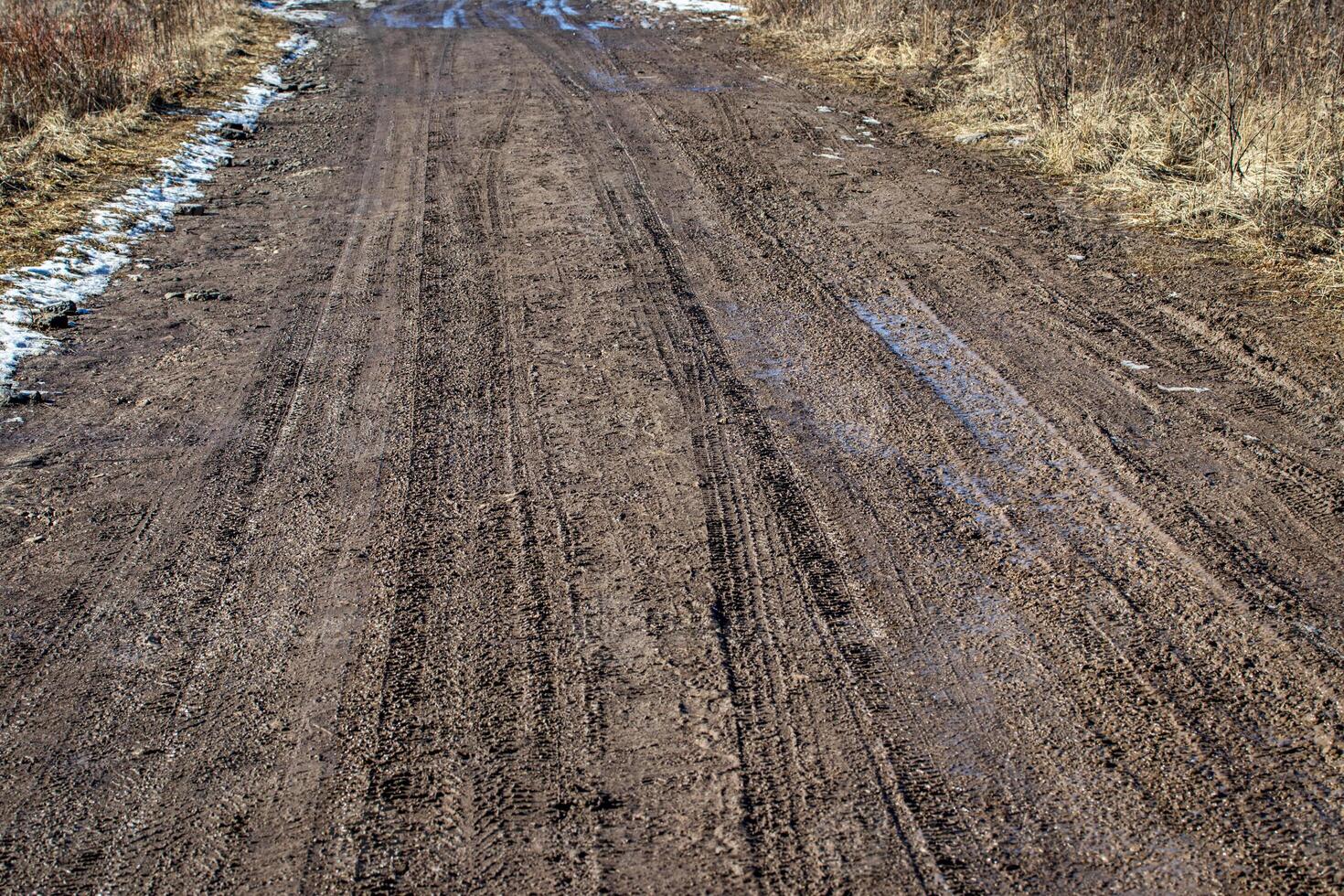 Dirty blurry dirt road with tire tracks in spring. photo