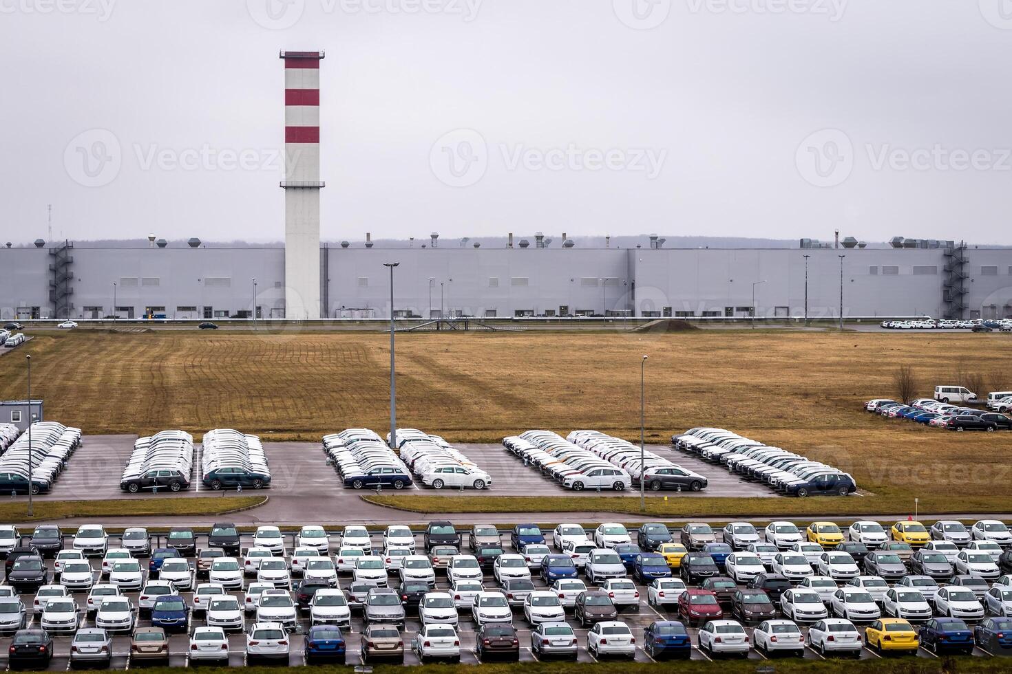New cars parked in a distribution center on a cloudy rainy day in the autumn, a car factory. photo