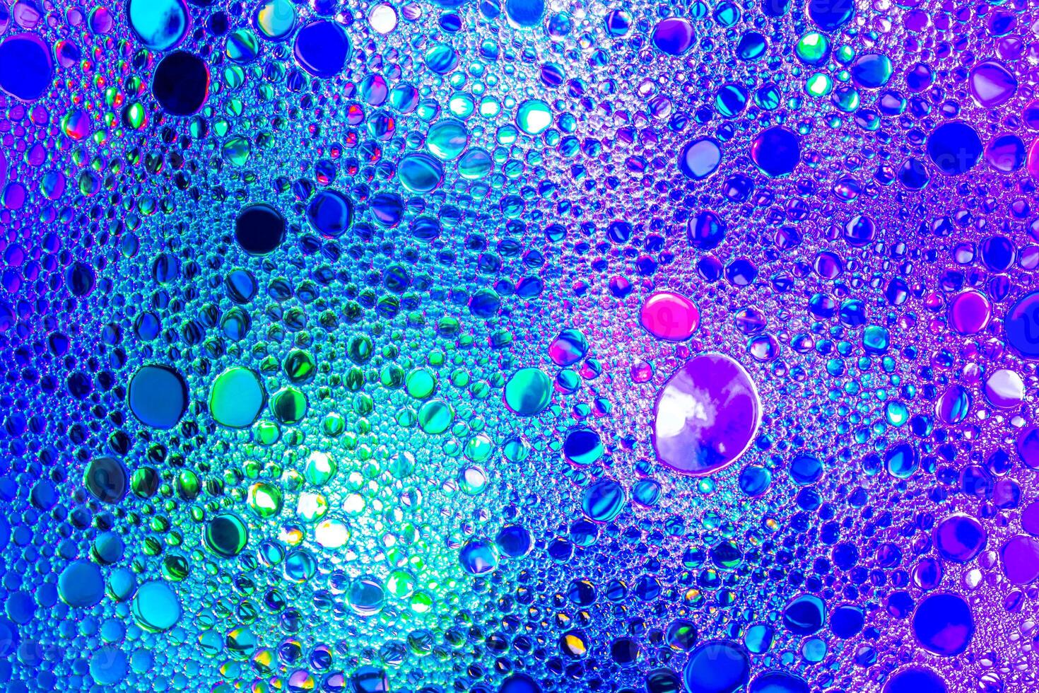 Colorful drops of oil on the water. Blue and violet colored circles and ovals. Abstract background for design. photo