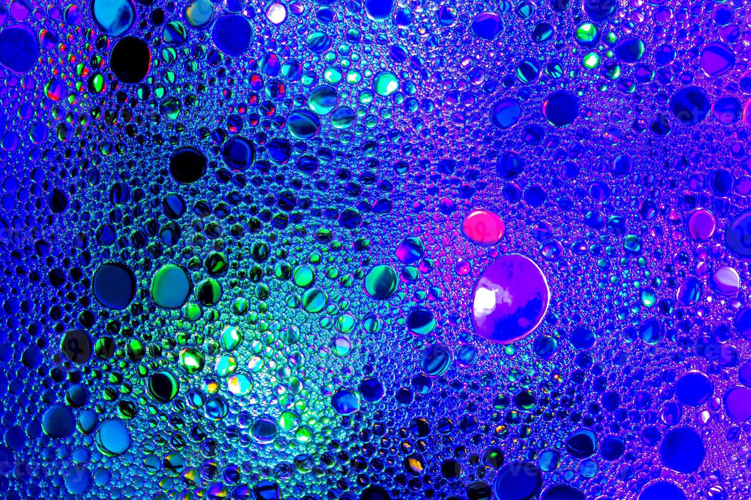 Colorful drops of oil on the water. Blue and violet colored circles and ovals. Abstract background for design. photo