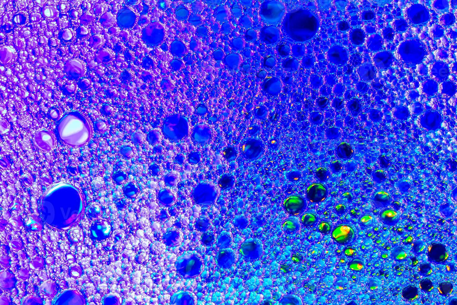 Colorful drops of oil on the water. Blue and violet colored circles and ovals. Abstract background for design. photo