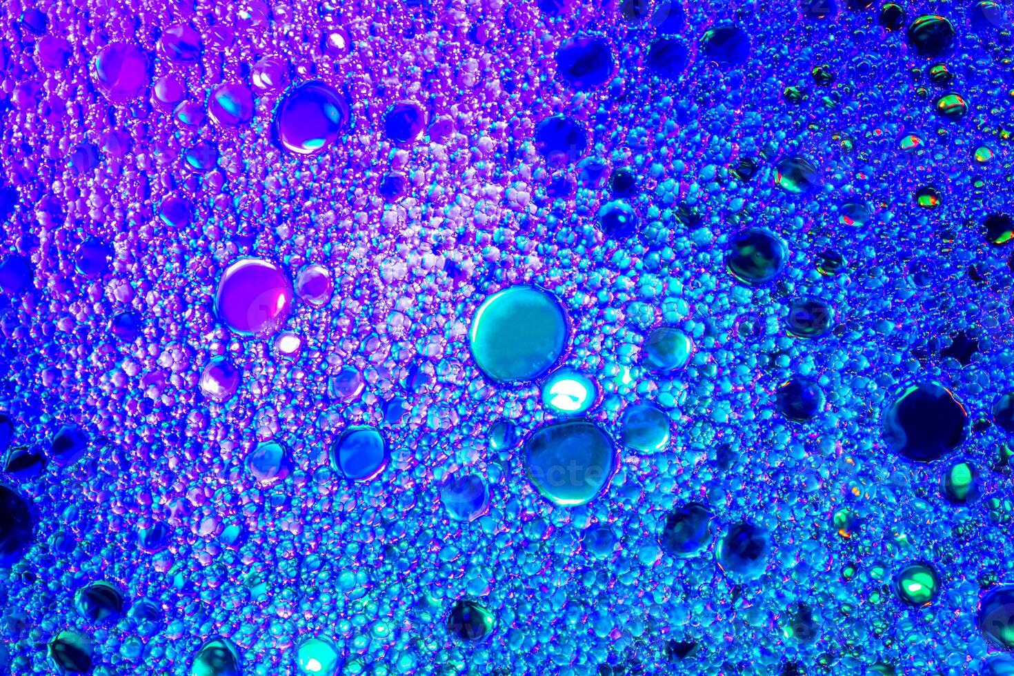 Colorful drops of oil on the water. Blue and violet colored circles and ovals. Abstract background for design. photo