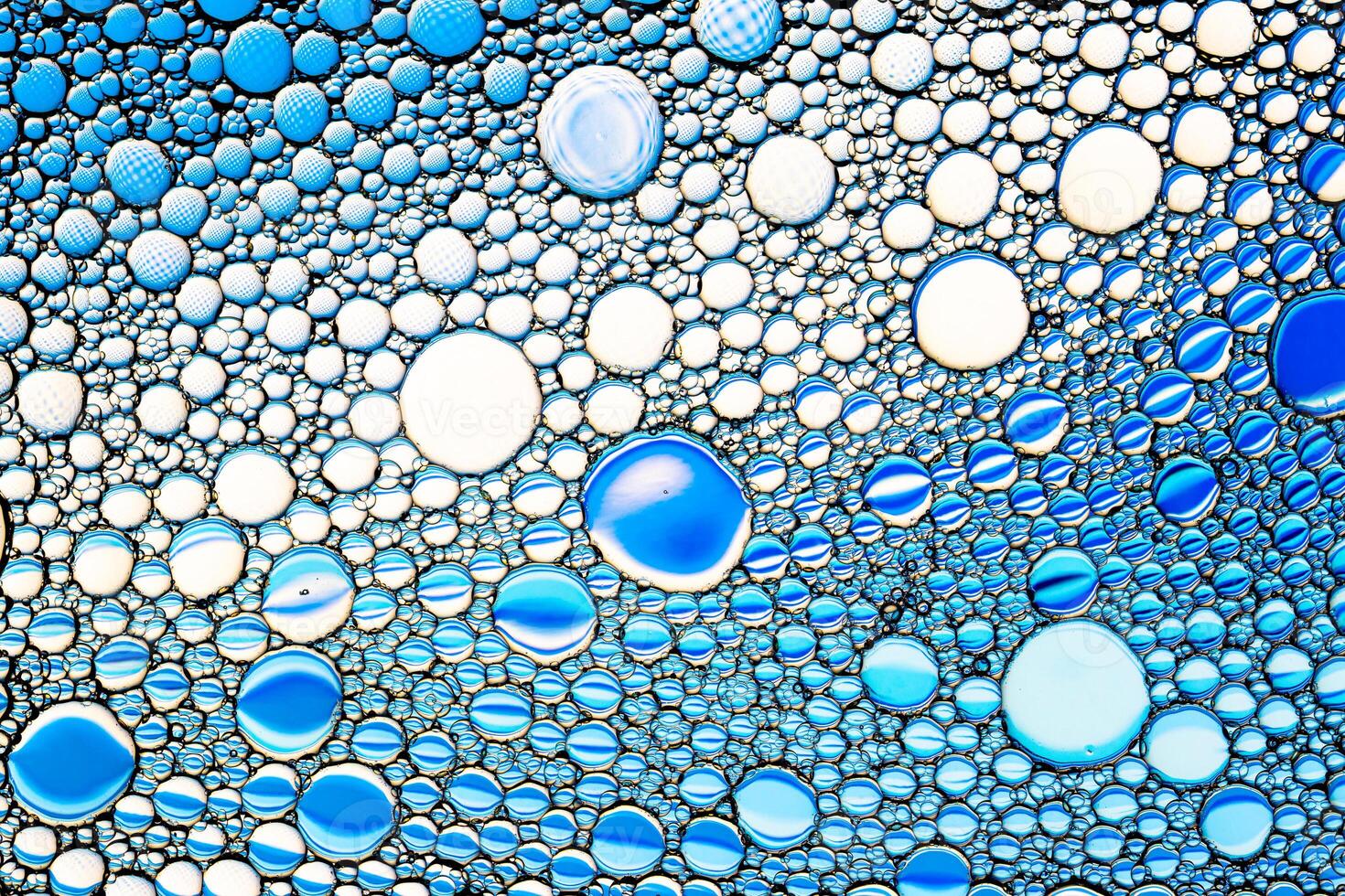 Top view on colorful drops of oil on the water. Blue circles and ovals. Abstract bright background for design. photo