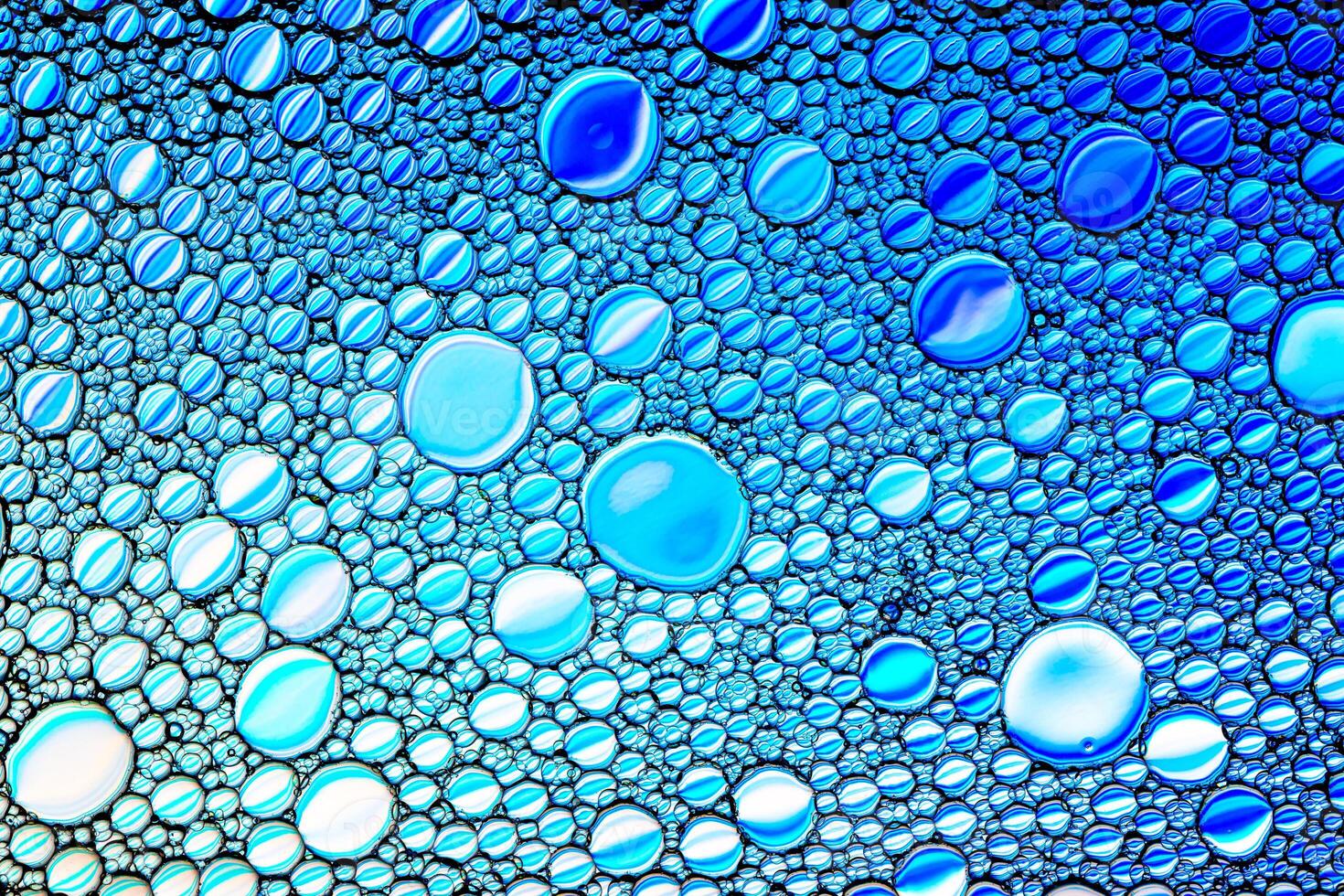 Top view on colorful drops of oil on the water. Blue circles and ovals. Abstract bright background for design. photo