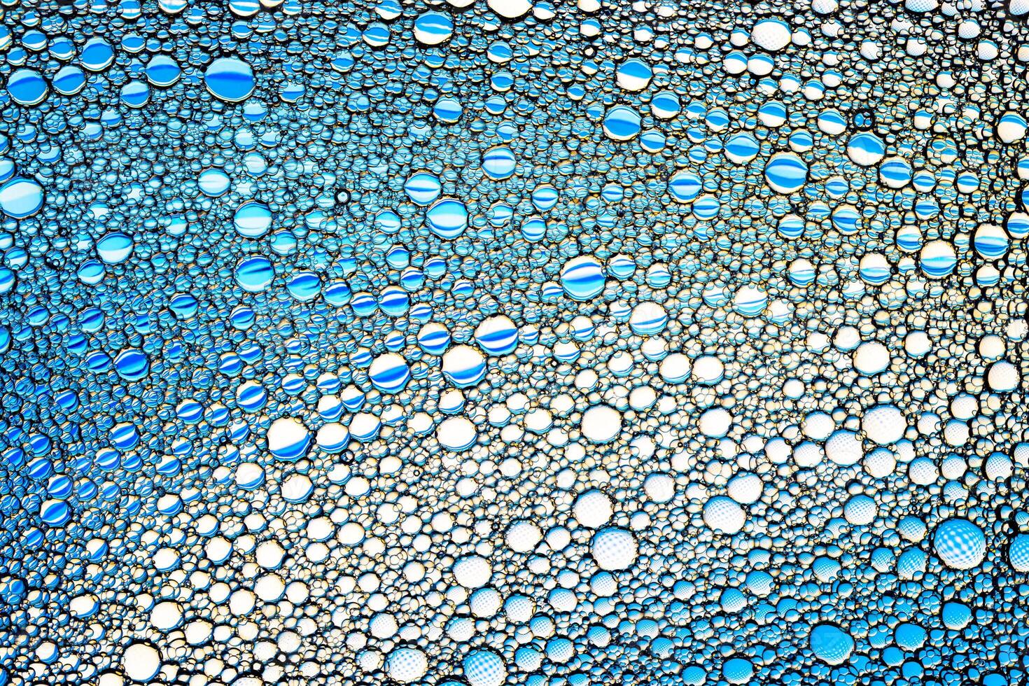 Top view on colorful drops of oil on the water. Blue circles and ovals. Abstract bright background for design. photo