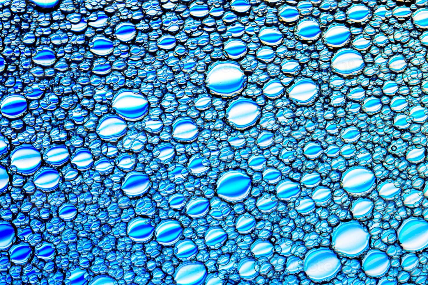 Top view on colorful drops of oil on the water. Blue circles and ovals. Abstract bright background for design. photo