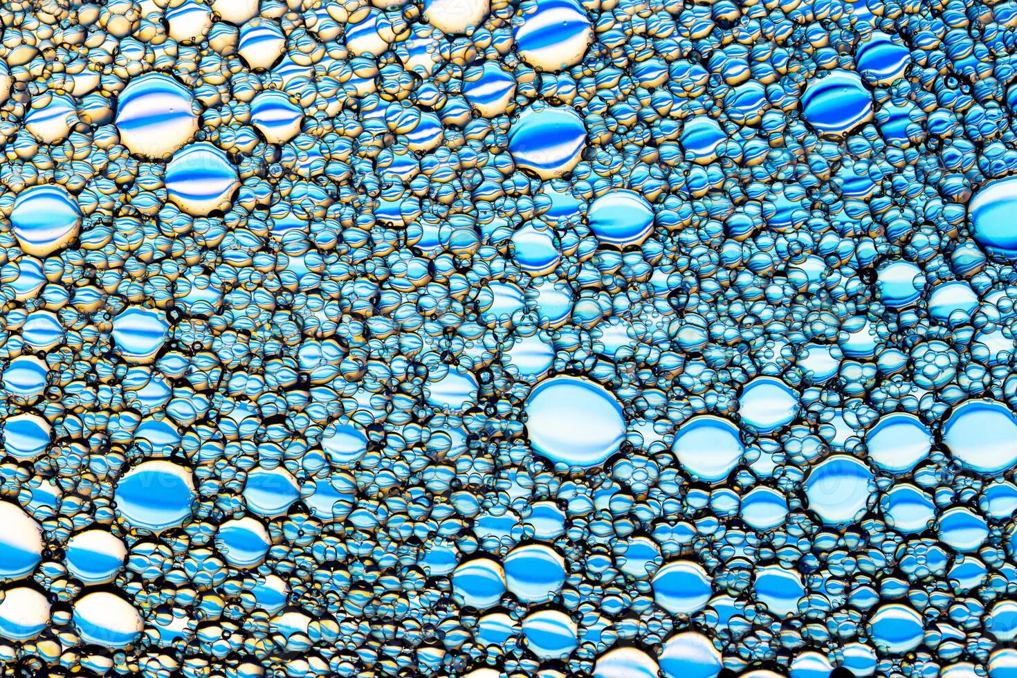 Top view on a colorful drops of oil on the water. Rainbow or spectrum colored circles, ovals. photo