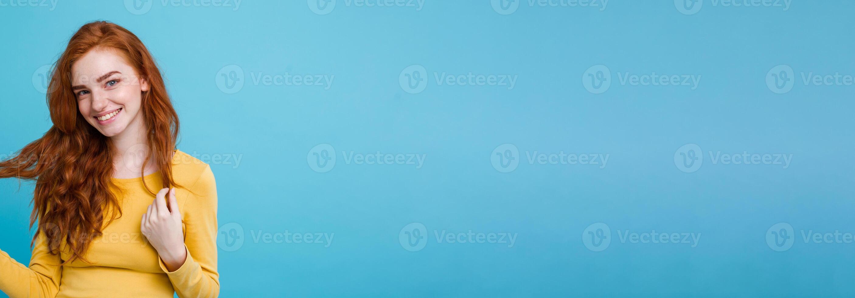 Portrait of happy ginger red hair girl with freckles smiling looking at camera. Pastel blue background. Copy Space photo
