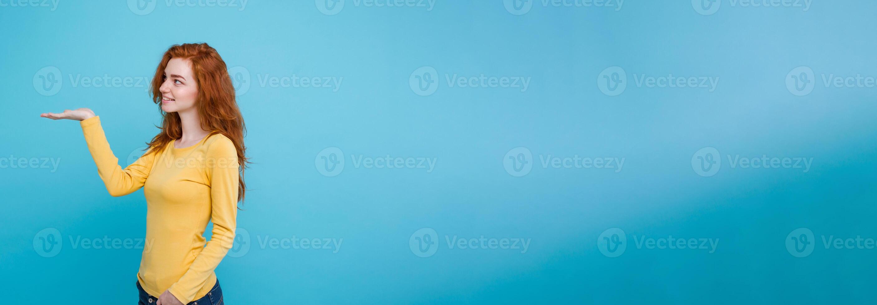 Close up Portrait young beautiful attractive redhair girl happy with something and pointing finger. Blue Pastel Background. Copy space photo