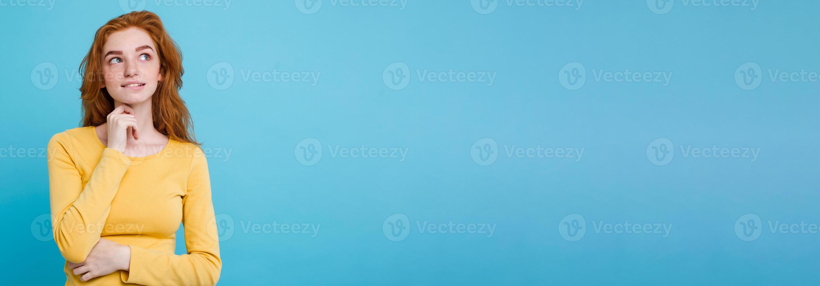 Portrait of happy ginger red hair girl with freckles smiling looking at camera. Pastel blue background. Copy Space photo