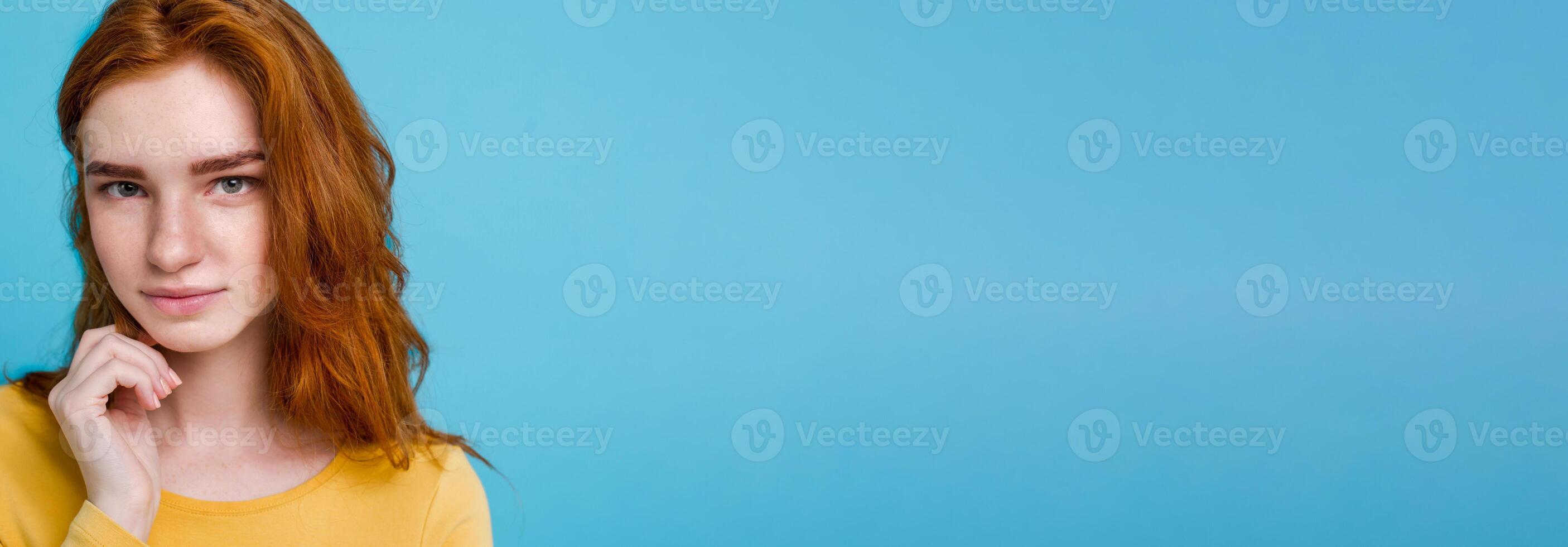 Headshot Portrait of happy ginger red hair girl with freckles smiling looking at camera. Pastel blue background. Copy Space photo