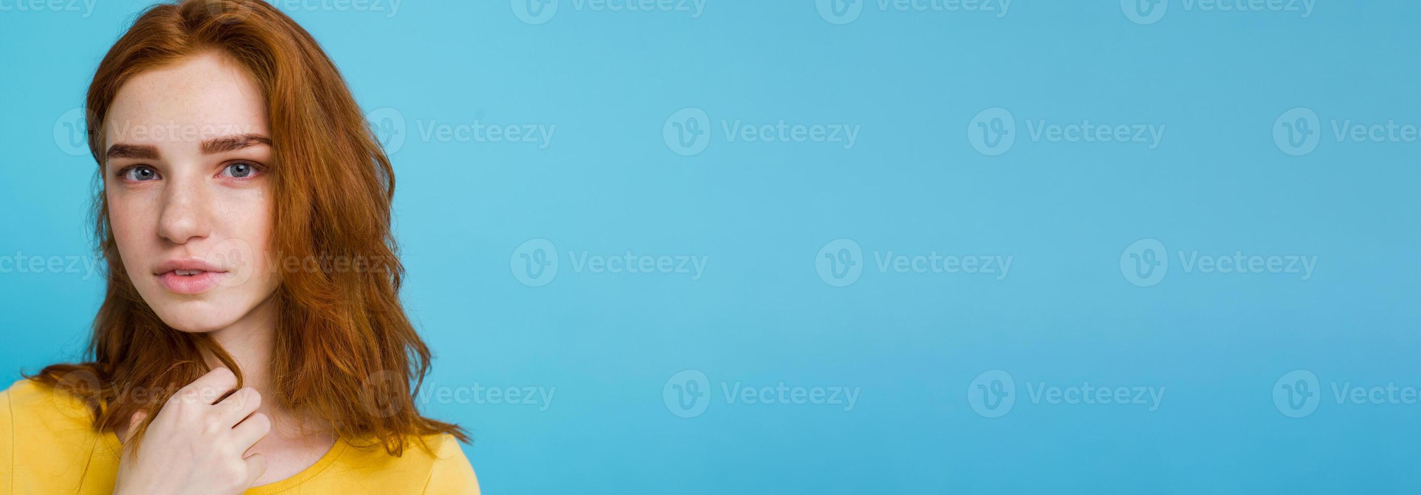 Headshot Portrait of happy ginger red hair girl with freckles smiling looking at camera. Pastel blue background. Copy Space photo