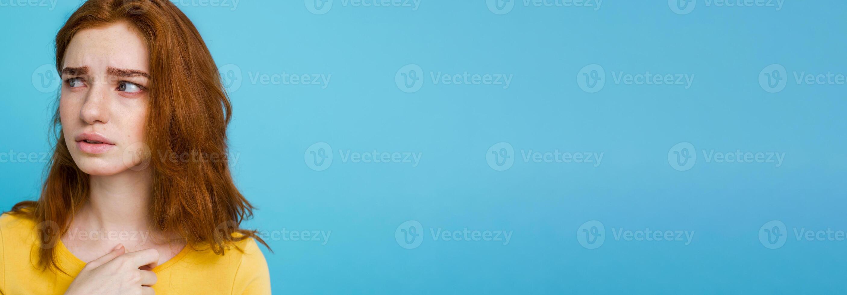 Headshot Portrait of happy ginger red hair girl with freckles smiling looking at camera. Pastel blue background. Copy Space photo