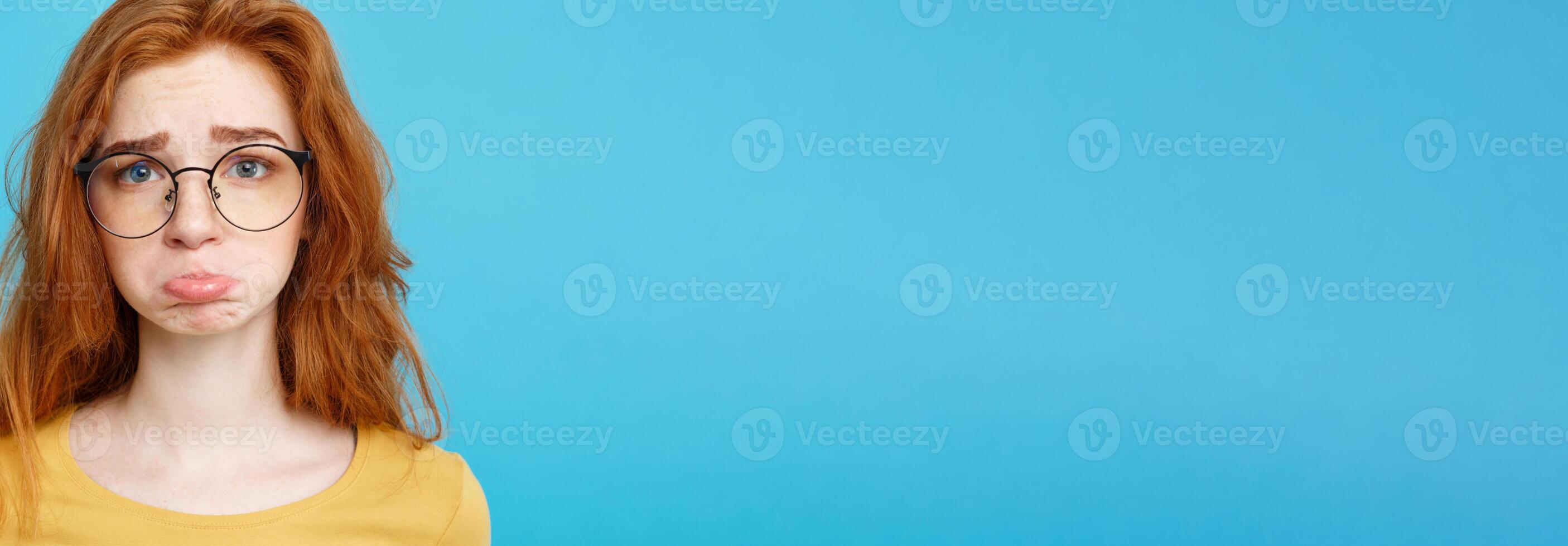 Headshot Portrait of happy ginger red hair girl with freckles smiling looking at camera. Pastel blue background. Copy Space. photo
