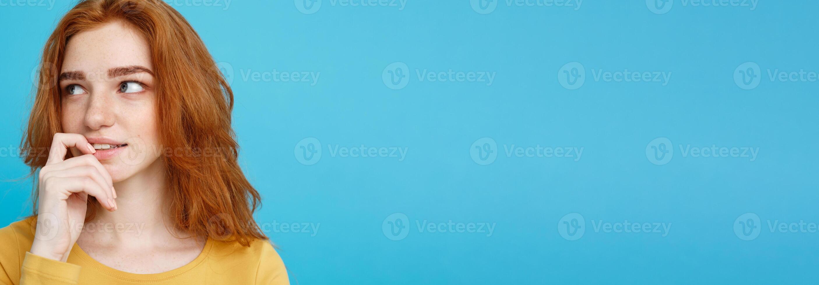 Headshot Portrait of happy ginger red hair girl with freckles smiling looking at camera. Pastel blue background. Copy Space. photo