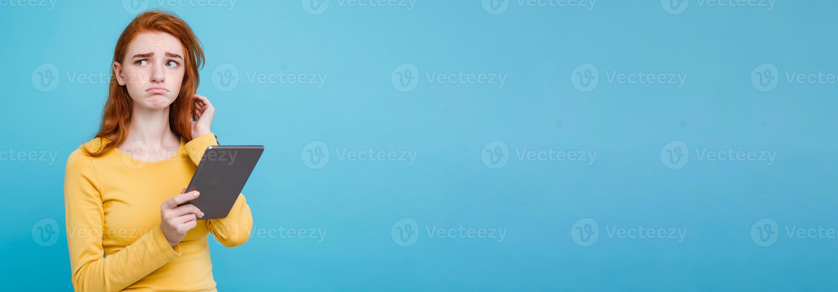 Close up Portrait young beautiful attractive tender ginger redhair girl happy smiling on digital table with wining something. Blue Pastel Background. Copy space photo
