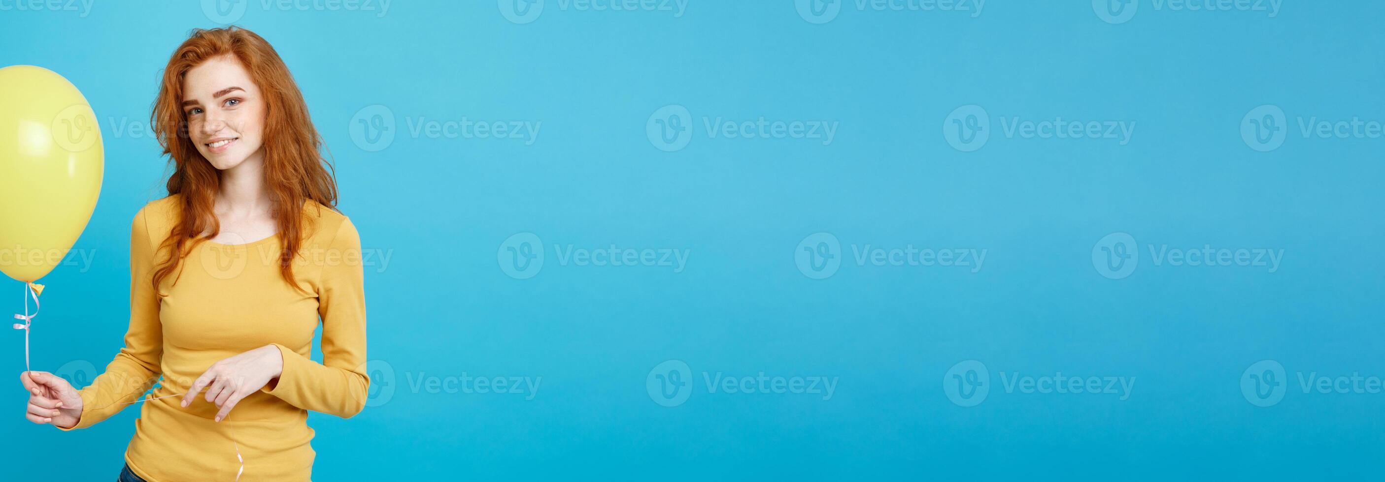 Celebrating Concept - Close up Portrait happy young beautiful attractive redhair girl smiling with colorful party balloon. Blue Pastel Background. photo