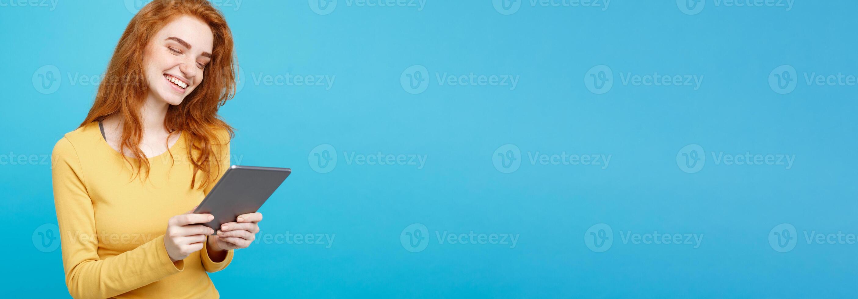 People and Technology Concept - Close up Portrait young beautiful attractive tender ginger redhair girl happy smiling on digital table with wining something. Blue Pastel Background. Copy space. photo