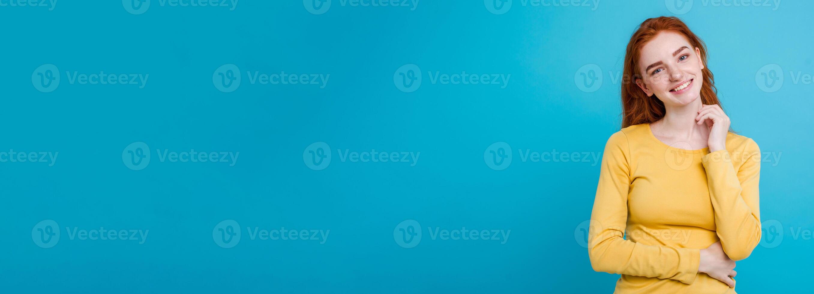 Portrait of happy ginger red hair girl with freckles smiling looking at camera. Pastel blue background. Copy Space photo