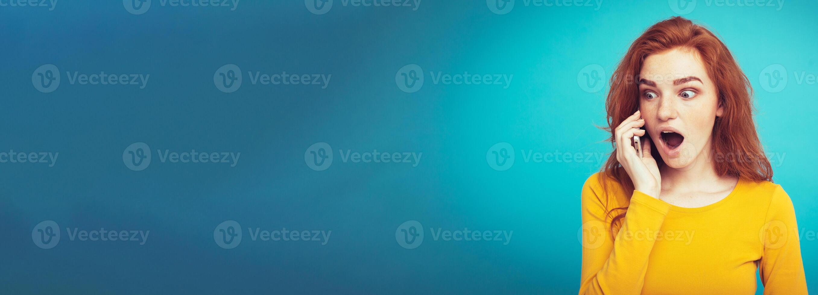 Lifestyle and Technology concept - Portrait of cheerful happy ginger red hair girl with joyful and exciting talking with friend by mobile phone. Isolated on Blue Pastel Background. Copy space photo