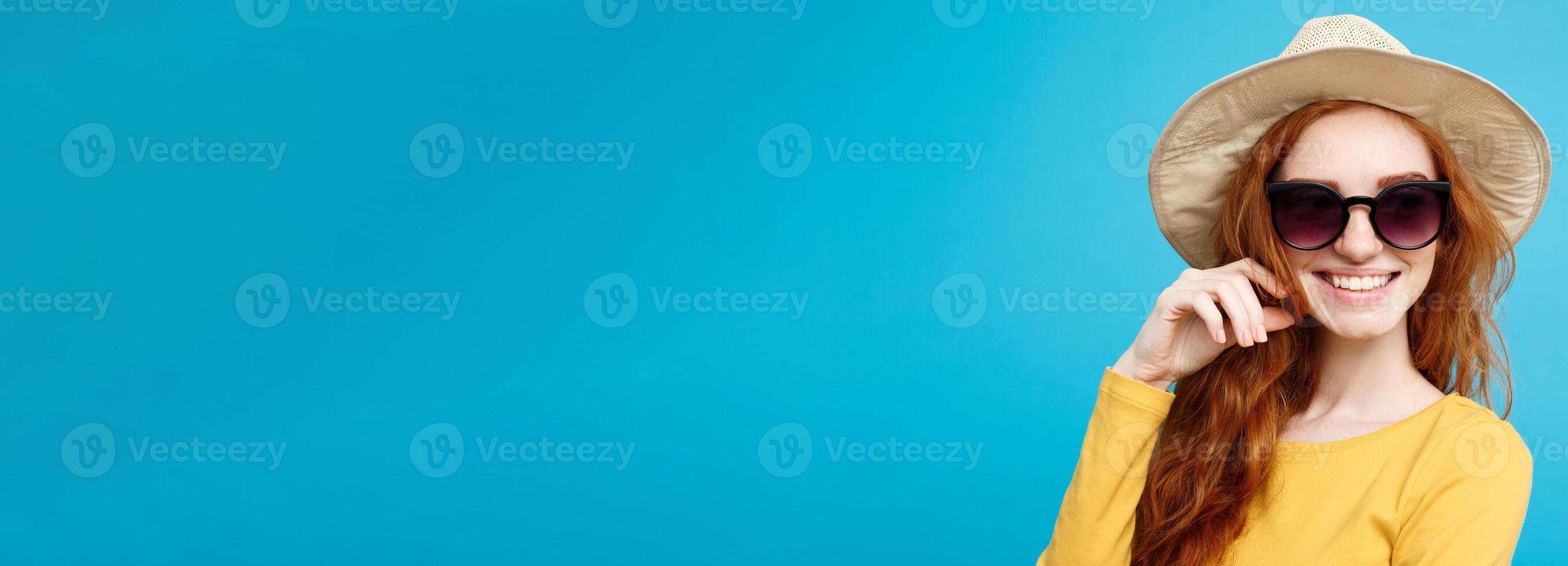 Travel concept - Close up Portrait young beautiful attractive ginger red hair girl with trendy hat and sunglass smiling. Blue Pastel Background. Copy space. photo